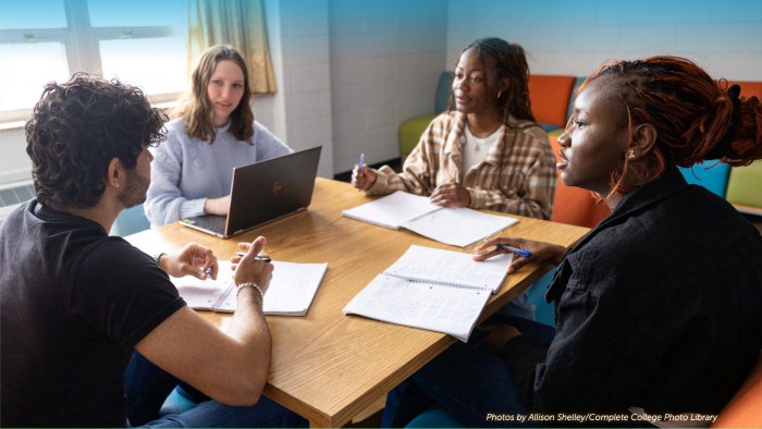 Four students are pictured sitting around a table in the library studying for an upcoming English exam.