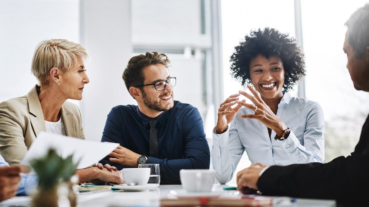 Two women and three men are pictured smiling and brainstorming ideas over coffee.