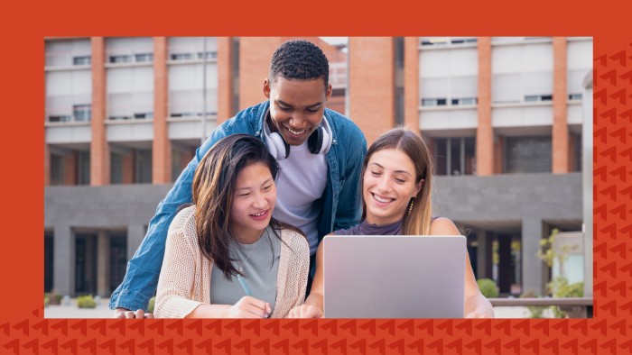 Three students, including one man and two women, gather around a laptop on a college campus. An orange border is applied to the image.