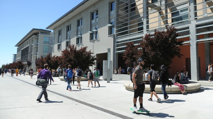 On a sunny day, students walk to class on a college campus.