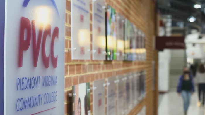 A hallway lined with plaques and students walking to class at Piedmont Virginia Community College.
