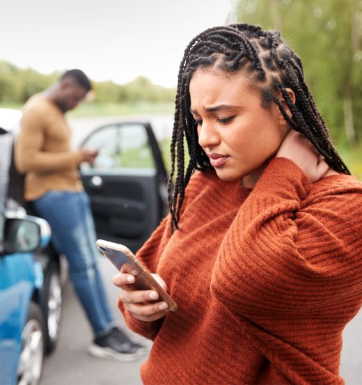 Stressed person next to a care on a mobile device.
