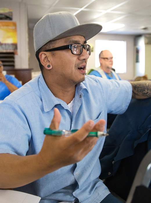 Person in a classroom setting with a pen in hand.